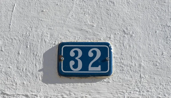 白墙上有蓝色背景的32个街号标志的特写镜头 — 图库照片
