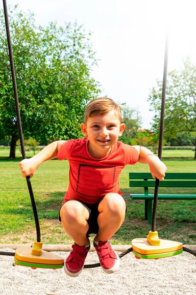 Niño Saltando Parque Infantil Vistiendo Camiseta Roja Sonriendo Día Soleado — Foto de Stock