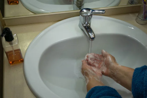 女人穿着蓝色浴衣 用肥皂洗手 — 图库照片