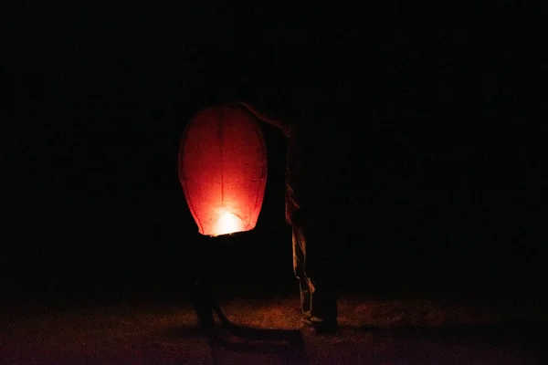一个男人拿着一盏天灯 准备在一个漆黑的夜晚放生 — 图库照片