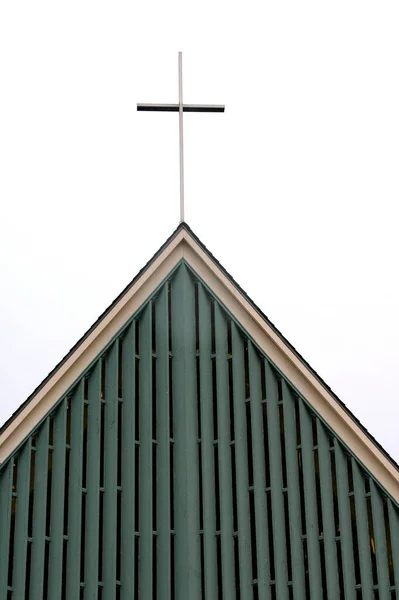 曇った空に対して建物の屋根の上に十字架の垂直ショット — ストック写真