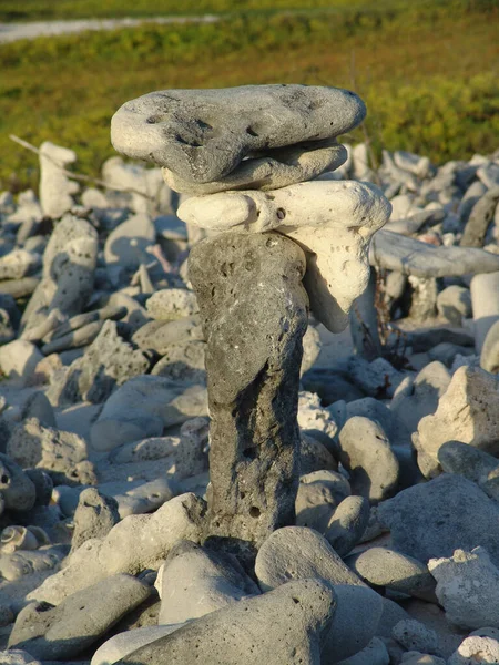 在阳光明媚的海岸上翻动的平衡石子的垂直镜头 — 图库照片