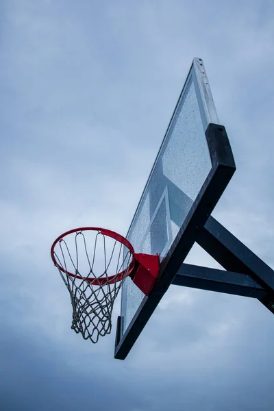 Ein Vertikaler Flachschuss Von Basketballkorb Und Netz Unter Wolkenverhangenem Himmel — Stockfoto