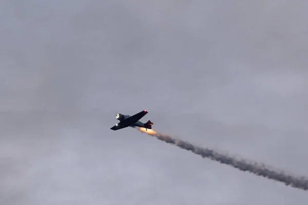 暗い空に対して煙を燃焼する空飛ぶ軍用機 — ストック写真