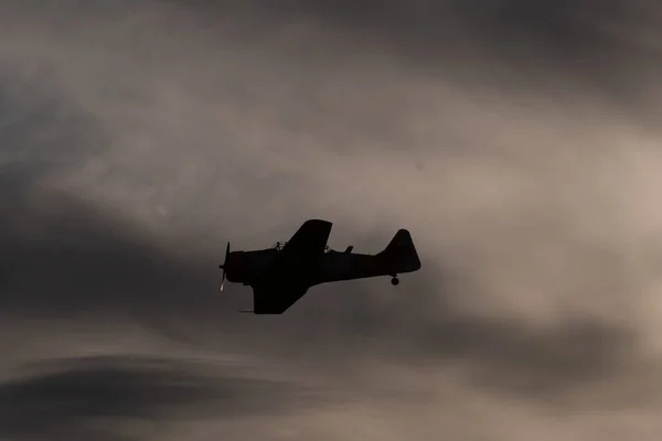 一架老式军用飞机在多云的天空中飞行的轮廓 — 图库照片