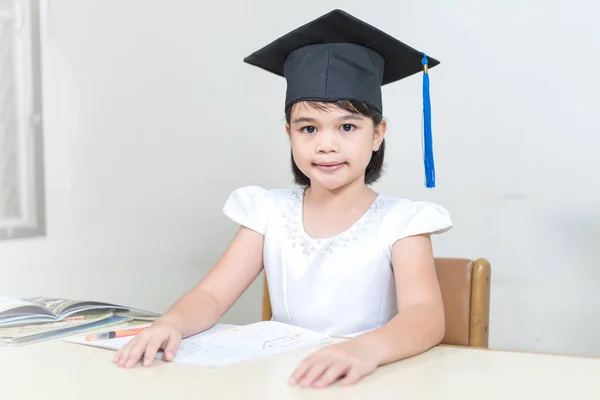 Retrato Uma Menina Asiática Vestindo Tabuleiro Argamassa Sentado Uma Mesa — Fotografia de Stock