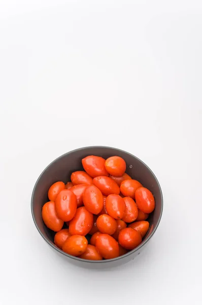 暗灰色的石器碗 盛满了西红柿 放在白色的表面 上面有文字空间 — 图库照片