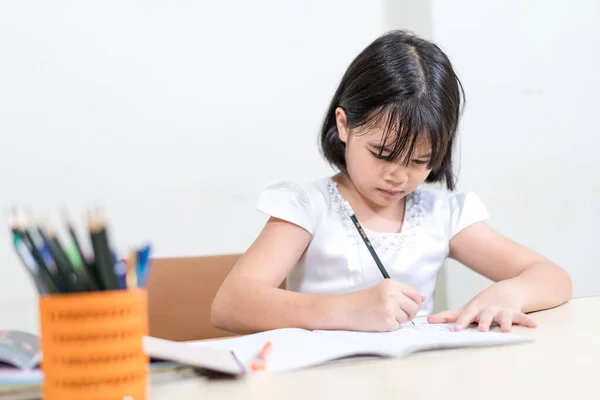 Маленькая Азиатская Девочка Сидит Столом Пишет Блокноте — стоковое фото