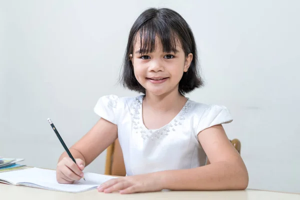 Retrato Una Niña Asiática Sonriente Sentada Junto Escritorio Escribiendo Copybook — Foto de Stock