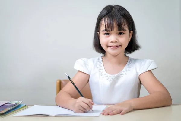 Портрет Улыбающейся Азиатской Девочки Сидящей Столом Пишущей Блокноте — стоковое фото