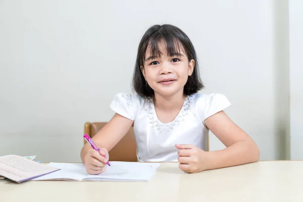 一个可爱的亚洲小女孩的肖像 坐在她的书桌旁边 研究着 — 图库照片