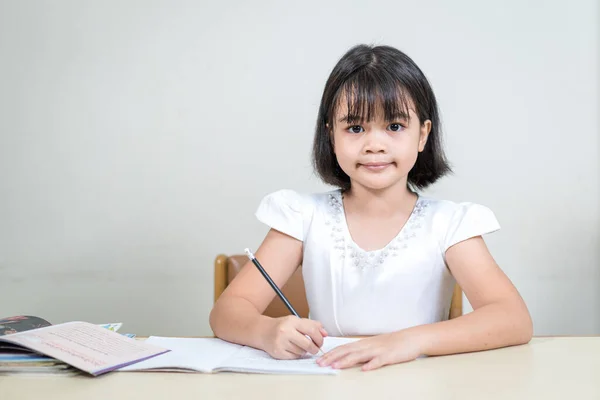 Портрет Усміхненої Азіатської Дівчинки Яка Сидить Столом Пише Своїй Книзі — стокове фото