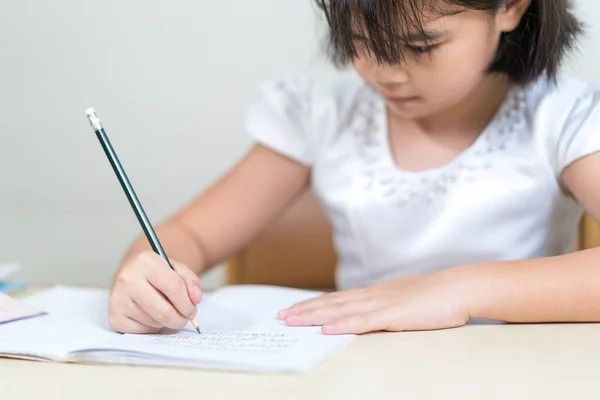 Una Niña Asiática Sentada Junto Escritorio Escribiendo Copybook Con Lápiz —  Fotos de Stock