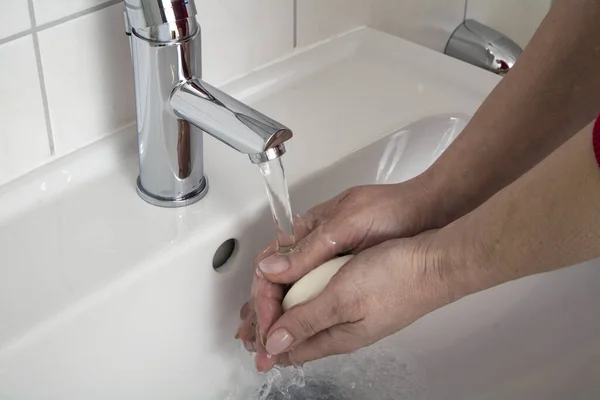 用肥皂在白色水槽里洗手的人 — 图库照片