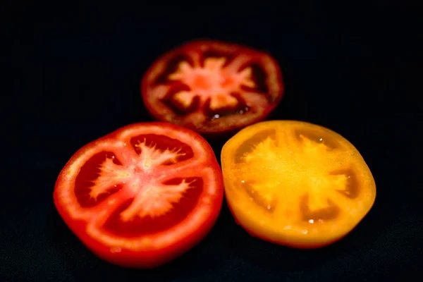 Drei Halbierte Tomaten Isoliert Auf Schwarzem Hintergrund — Stockfoto