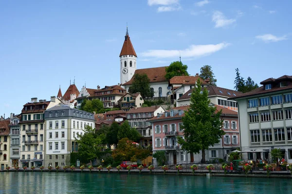 A view of a Thun Castle among the small buildings in front of a river in Switzerland