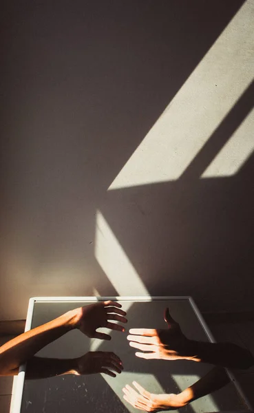 Pionowe Ujęcie Rąk Dwojga Ludzi Sięgających Siebie Świetle Słonecznym — Zdjęcie stockowe