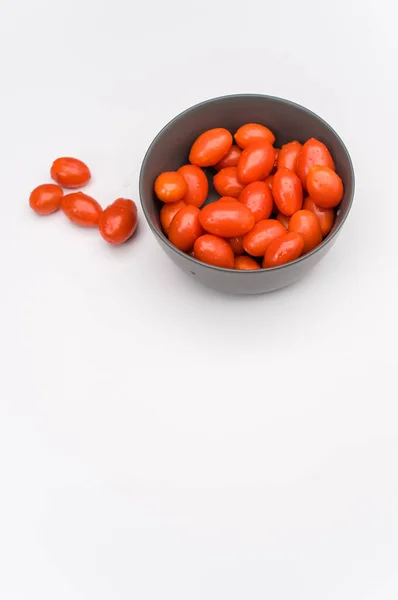 暗灰色的石器碗 盛满了西红柿 放在白色的表面 上面有文字空间 — 图库照片