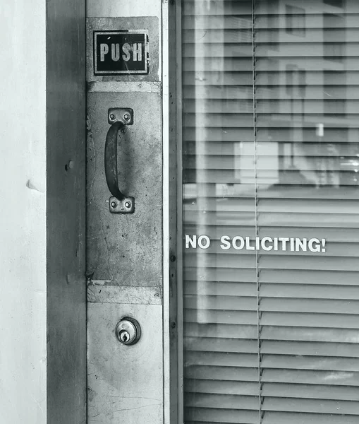 A glass door is labeled with push and no soliciting notices