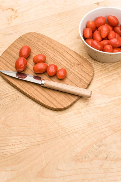 Tazón Lleno Tomates Datterini Con Tabla Cortar Cuchillo Una Superficie —  Fotos de Stock