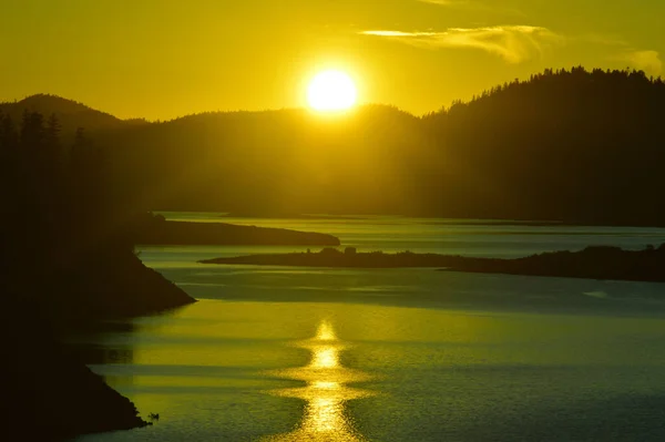 夕阳西下 群山上的灿烂阳光映照在平静的海面上 — 图库照片