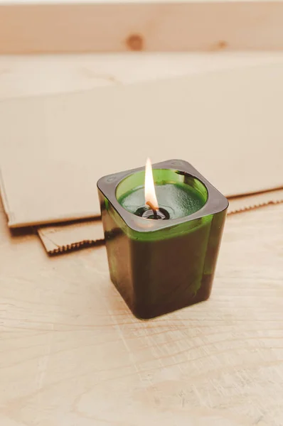 scented candle in a green glass burning on a rustic wooden tabletop with copy space