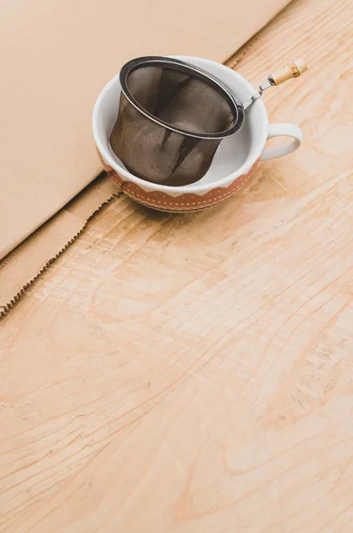 Metal Tea Strainer Decorated Tea Cup Kraft Paper Wooden Background — 스톡 사진