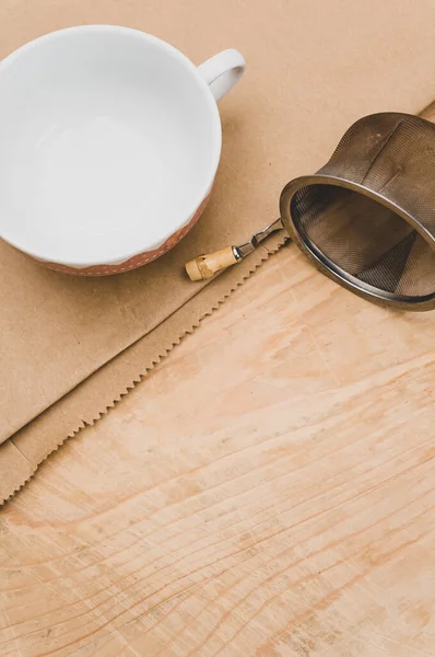 Metal Tea Strainer Decorated Tea Cup Kraft Paper Wooden Background — Stock Fotó