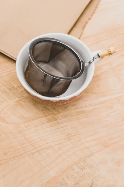 Metal Tea Strainer Decorated Tea Cup Kraft Paper Wooden Background — ストック写真