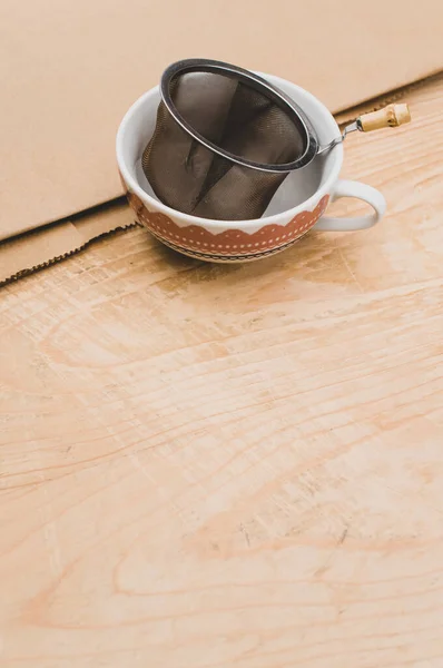 Metal Tea Strainer Decorated Tea Cup Kraft Paper Wooden Background — Stock Fotó