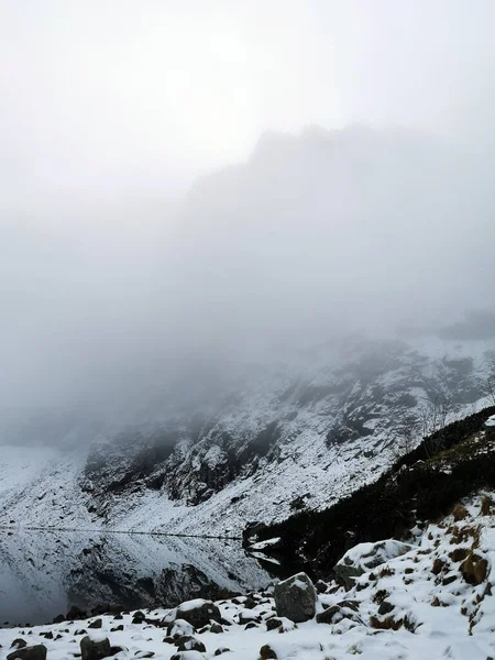 透过薄雾看得见的白雪覆盖的海滨小山 — 图库照片