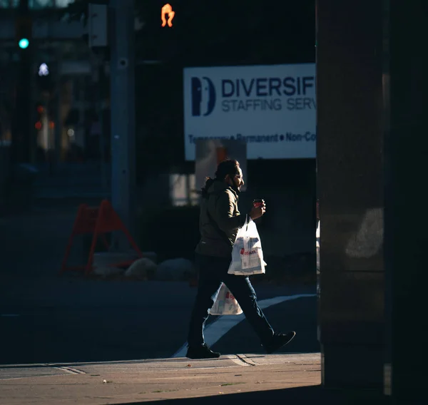 Calgary カナダ 2021年10月16日 晴れた日にカルガリーの通りを歩くビニール袋を持つ女性の側面図 — ストック写真