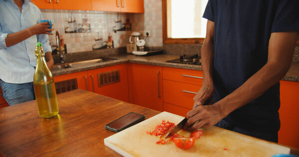 Young Man Cutting Tomatoes Board While Talking His Friend Royalty Free Stock Photos