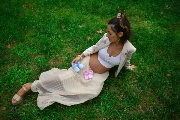 Ładna Młoda Biała Kobieta Ciąży Pozująca Parku Dziecięcymi Butami — Zdjęcie stockowe