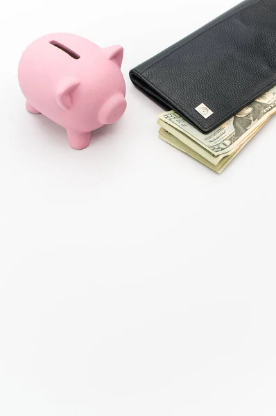一个可爱的粉色储蓄罐 钱包和钞票堆在有复制空间的白色桌面上 — 图库照片