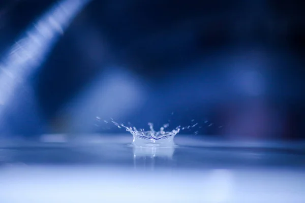 Een Close Shot Van Een Waterdruppel Geïsoleerd Een Blauwe Achtergrond — Stockfoto