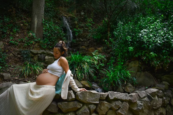 돌벽에 기대어 자연스럽게 포즈를 취하는 아름다운 임산부 — 스톡 사진