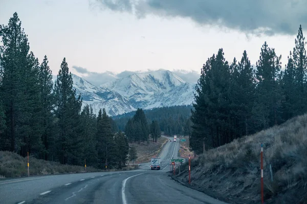 Estrada Tráfego Longo Densa Floresta Com Montanhas Nevadas Fundo Dia — Fotografia de Stock