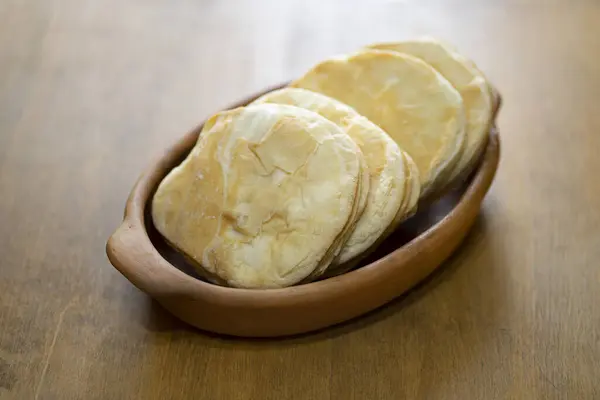 木桌上的粗粘土碗中的面包片 — 图库照片