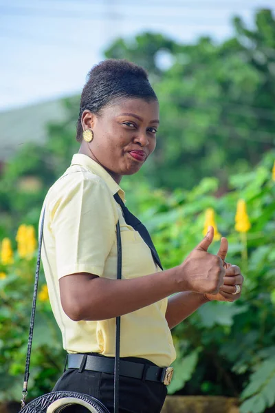 Eine Afrikanerin Uniform Und Mit Zwei Daumen Gestikulierend lizenzfreie Stockbilder