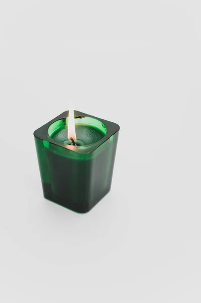 在白色背景的玻璃杯中孤立地燃烧着芬芳的绿色蜡烛 — 图库照片