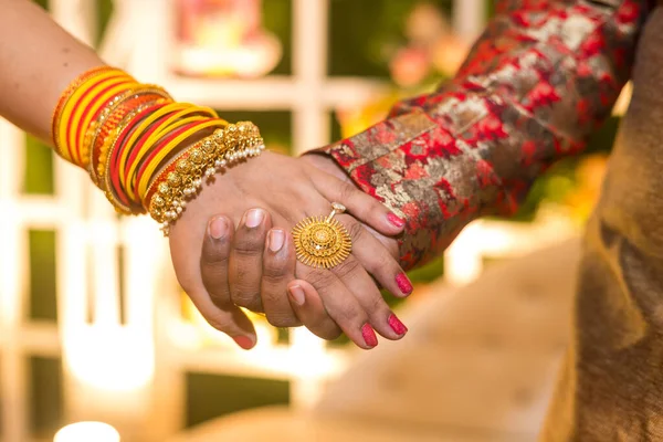 A man and a women holding hands in an Indian wedding looking for their future ahead.............