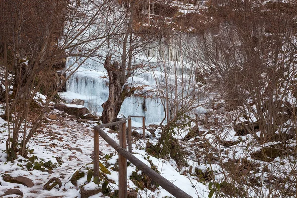 雪に覆われた道と木製のフェンスは 冬の間に風光明媚な美しい凍結森林滝につながります 有名なツパヴィツァの滝 セルビア — ストック写真