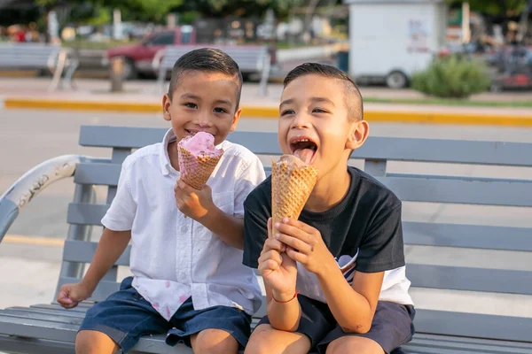 Duas Crianças Hispânicas Alegres Sentadas Banco Parque Comendo Sorvete — Fotografia de Stock