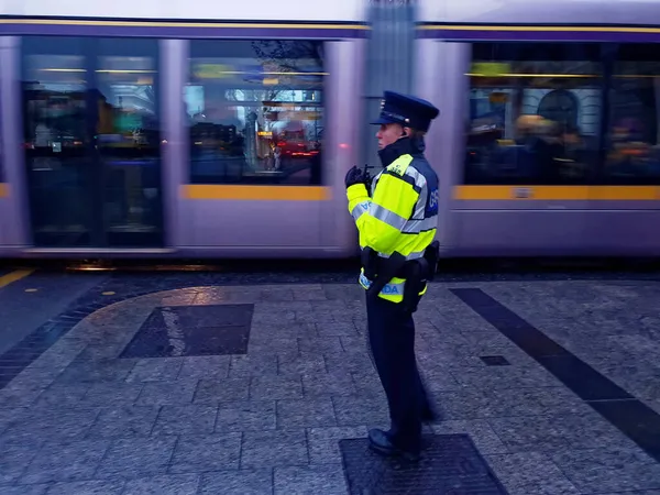 Dublin Ireland 2019年12月17日 有选择地关注都柏林市中心的爱尔兰警官 Garda Siochana 背景中移动有轨电车 Luas — 图库照片