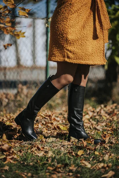 秋の葉を歩きながら黒いファッショナブルなブーツを着た女性 — ストック写真