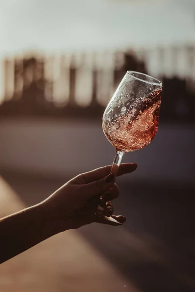 Вертикальний Знімок Скляного Поля Трояндовим Вином Тримається Жіночою Рукою Розмитому — стокове фото