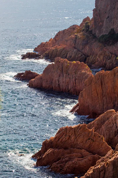 Eine Vertikale Aufnahme Von Meereswellen Die Über Rote Felsen Spritzen — Stockfoto