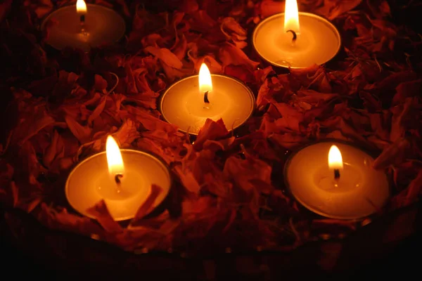 在盛满了水的碗里 用点燃的茶点 点燃的蜡烛和红润的花瓣做成的衣服 — 图库照片
