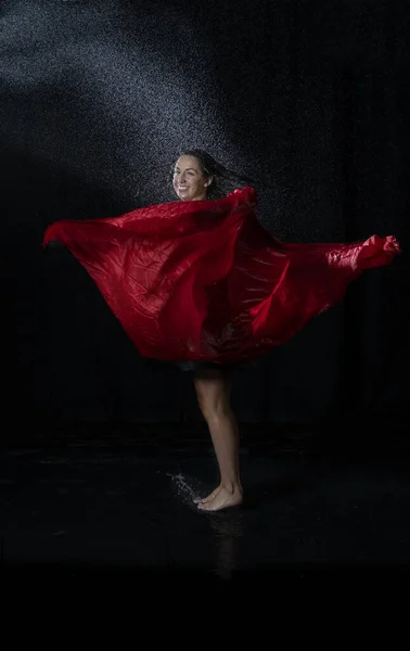 黒いドレスを着た濡れた髪をしたダンサーが水を楽しんで赤いスカーフで踊る — ストック写真